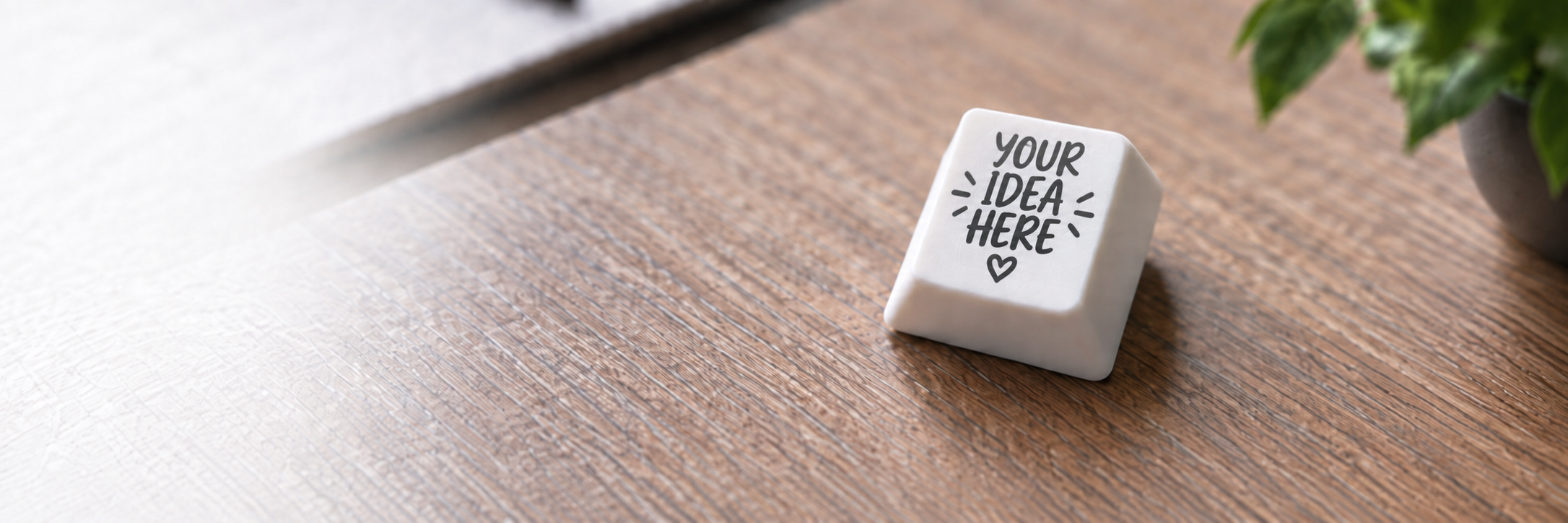White custom keycap reading Your Idea Here on a wooden desk